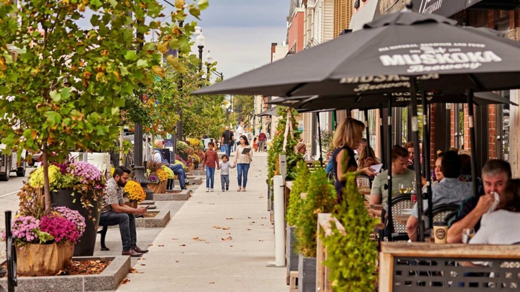 Tree lined street with boutique shops and pedestrians in Downtown Oakville Ontario